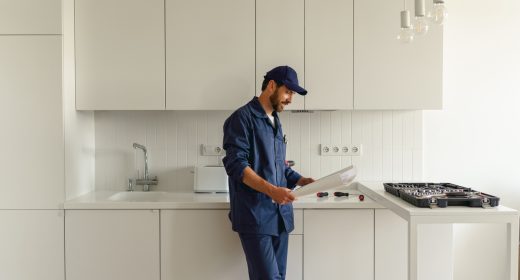 Handyman in uniform standing on kitchen with home plan before starting work Handyman in uniform standing on kitchen with home plan before starting work. High quality photo